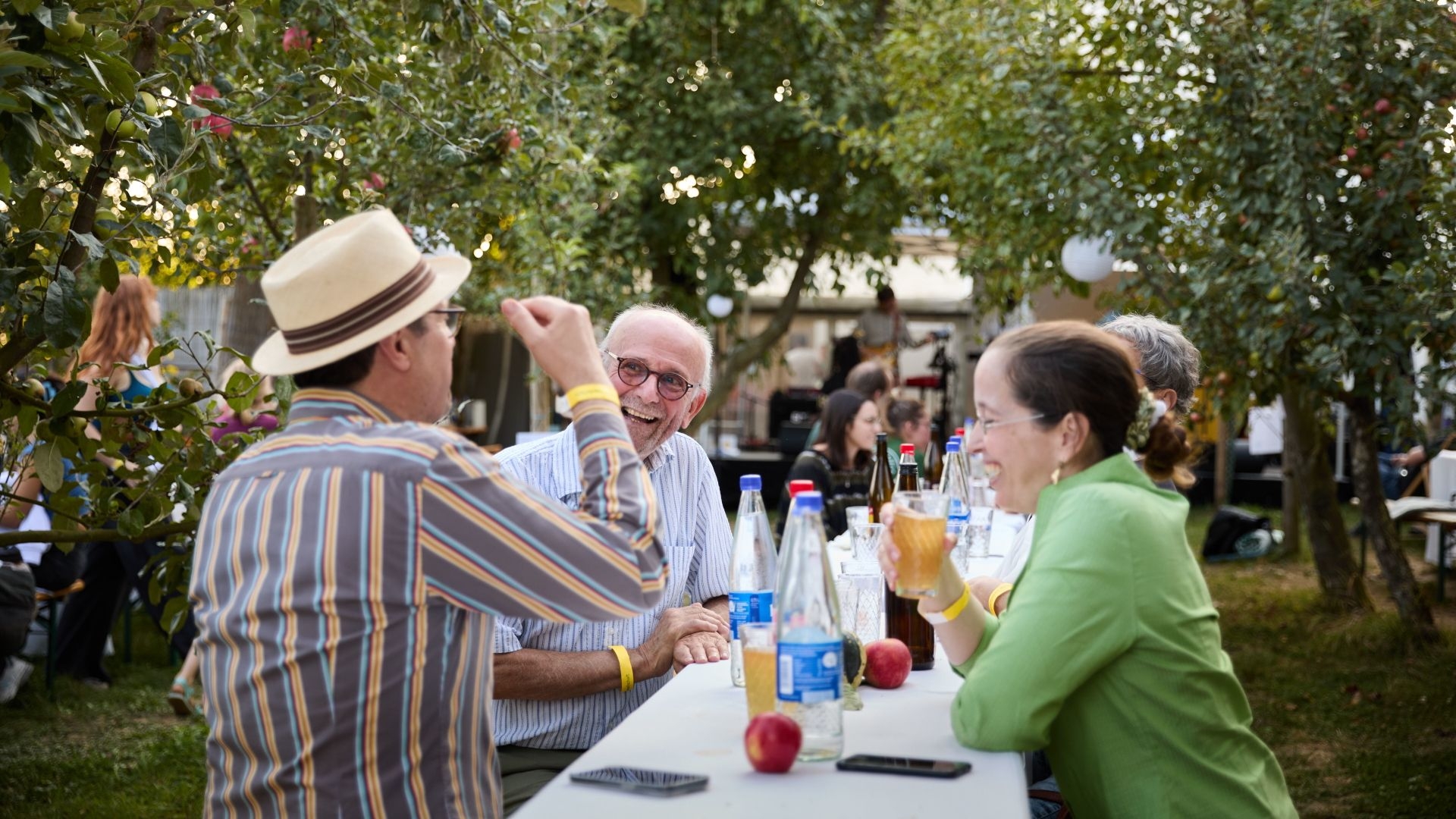 Beim Alumnitag der Stiftung sitzen Menschen beisammen im Apfelheim. Sie lachen und unterhalten sich.