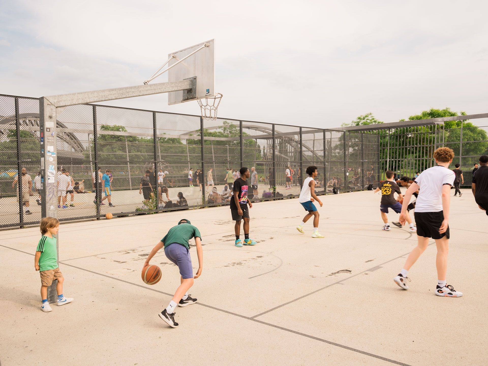 Jugendliche spielen auf einem Sportplatz Basektball.