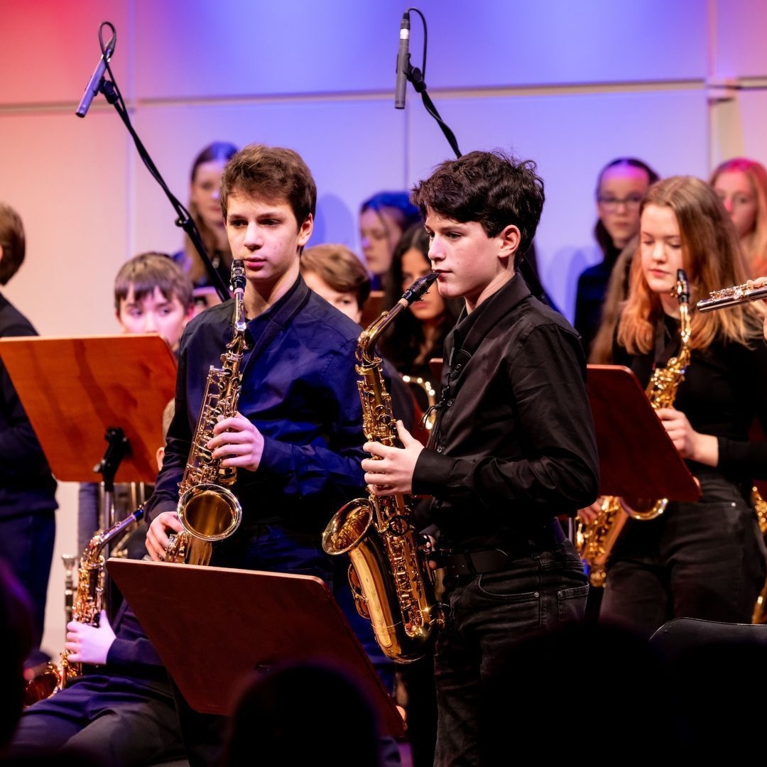 Jugendliche musizieren im Orchester mit Saxophon und Querflöte.
